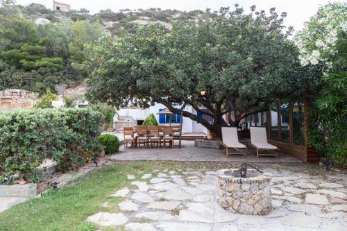 a patio with a tree and a table and chairs at Varkospito in Ierápetra