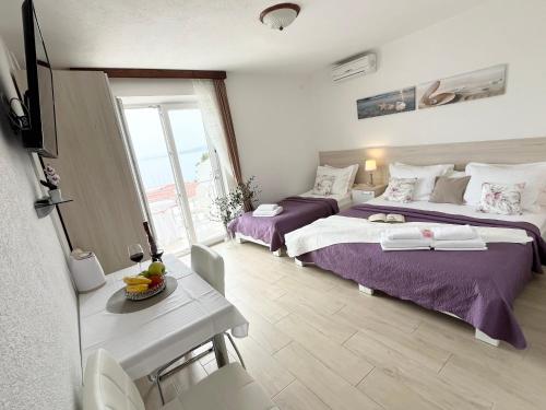 Habitación de hotel con 2 camas y mesa en Apartments Irma, en Baška Voda