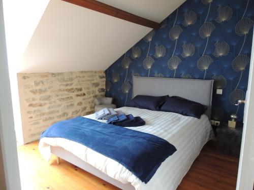 Un dormitorio con una cama con una pared azul. en Mas de Rossignol, en Vailhourles