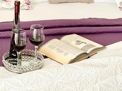 Una cama con dos copas de vino y un libro en Apartments Irma, en Baška Voda