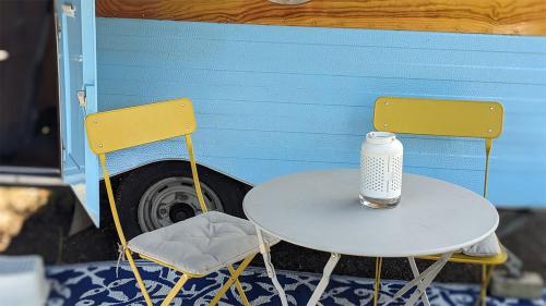 a white table and two chairs with a bottle on it at Cabrio-Wohnwagen in Brandenburg an der Havel