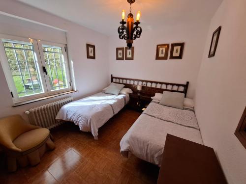 a bedroom with two beds and a chair and a chandelier at La Vista de Gredos in Navarredonda de Gredos
