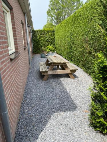 uma mesa de piquenique de madeira ao lado de uma parede de tijolos em La-Perchade em Huissen