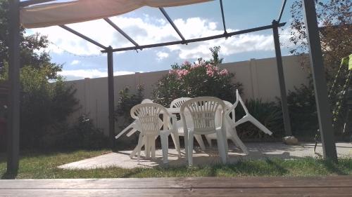 trois chaises blanches et une table sous un auvent dans l'établissement L'Olivier, au Mans