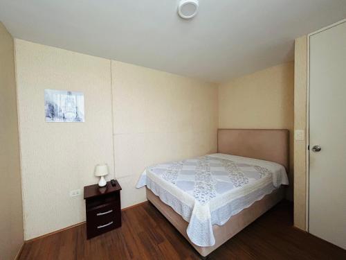 um pequeno quarto com uma cama e uma mesa de cabeceira em Departamento en Condominio Comas em Lima