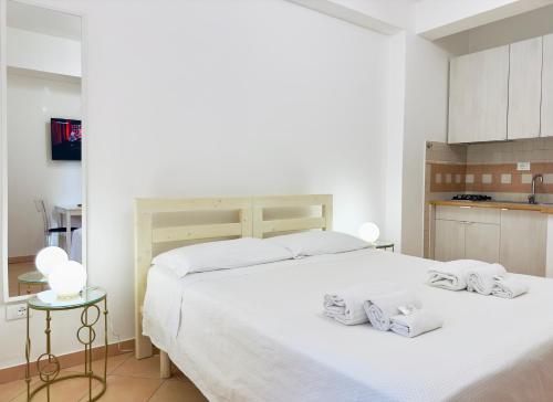 a white bedroom with two beds and a kitchen at ELLE Monolocale - Sperlonga 50 mt dalla spiaggia con parcheggio in Sperlonga