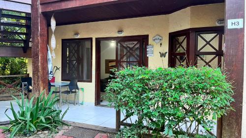 a front door of a house with a bush in front at Casa Maresias Canto do mar - 50m da praia in Maresias