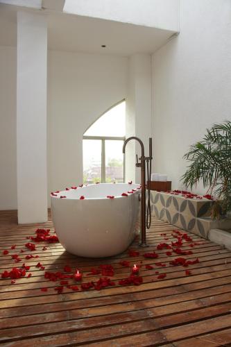 baño con bañera con pétalos de rosa roja en el suelo en Country International Hotel, en Barranquilla