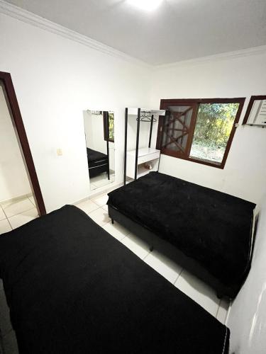 a bedroom with a black bed and a mirror at Casa Maresias Canto do mar - 50m da praia in Maresias