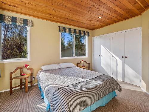 Waitahanui的住宿－Absolute Waterfront with WiFi - Five Mile Bay Home，一间卧室设有一张床和两个窗户。