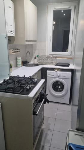 une cuisine avec une cuisinière et une machine à laver dans l'établissement Maison Cocon, à Pantin