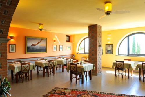 uma sala de jantar com mesas, cadeiras e janelas em B&B Villa Sensi em Tuoro sul Trasimeno