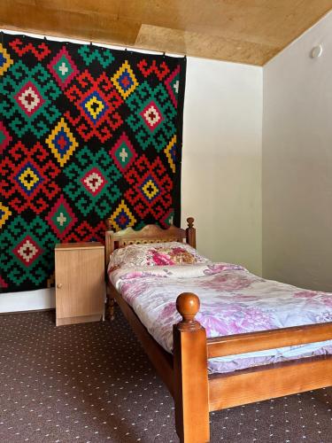 ein Schlafzimmer mit einem Bett und einer Decke an der Wand in der Unterkunft Shodmon Guesthouse in Jizzax