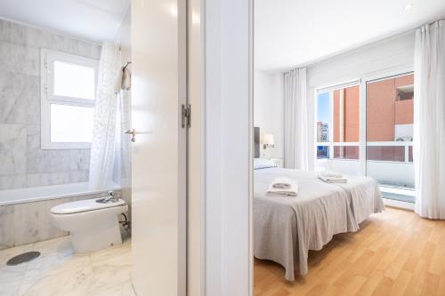 a white room with a bed and a window at Apartamentos Les Dunes Centro Levante Beach in Benidorm