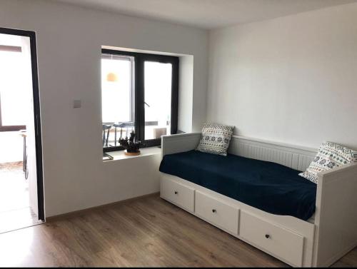 a white bedroom with a bed and two windows at Studio with a sea view in Balchik