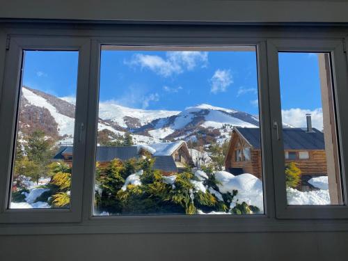 una ventana con vistas a una montaña nevada en Catedral Sur departamento en Bariloche en San Carlos de Bariloche