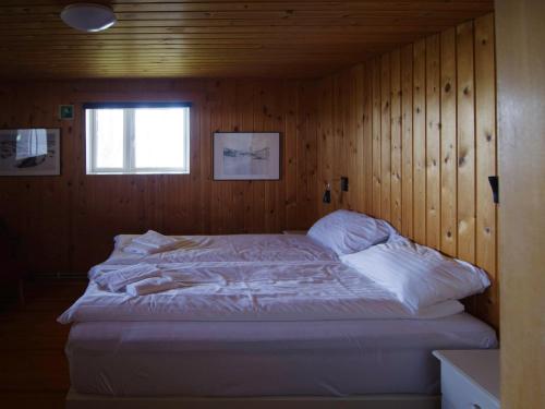 a bedroom with a large bed in a wooden wall at Myvo The House Geiteyjarströnd 4 in Geiteyjarstrond