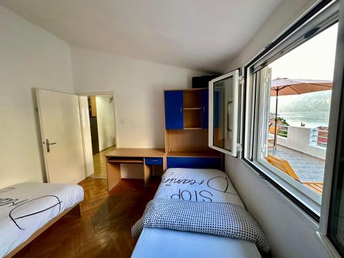 Pokój z 2 łóżkami, biurkiem i oknem w obiekcie House with big terrace and beautiful sea view w Kotorze
