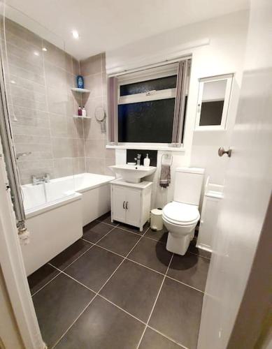 a bathroom with a toilet and a tub and a sink at Seaview Self Catering-Fleetview in Weymouth