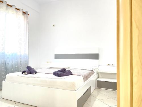a white bedroom with a bed with towels on it at Ernest Apartments in Sarandë