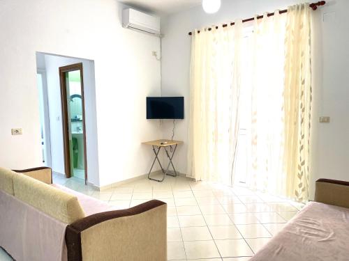 a living room with a couch and a tv at Ernest Apartments in Sarandë