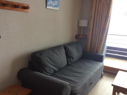 - un canapé bleu dans le salon doté d'une fenêtre dans l'établissement Le Corbier, bel appartement bien exposé, à Villarembert