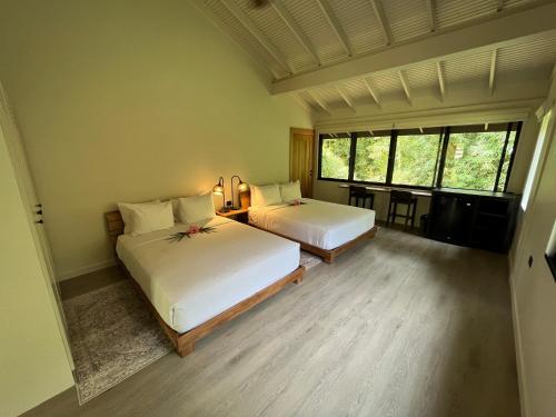 a bedroom with two beds and a table with chairs at HADCO Experiences at Asa Wright Nature Centre in Blanchisseuse