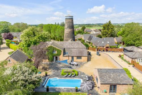 an aerial view of a house with a pool and a lighthouse at The Old Mill, 7 storey,, dog friendly outdoor pool & bbq in Stoke Ferry