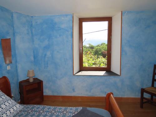 a bedroom with a blue wall with a window at Gîte du Verger in Soulan