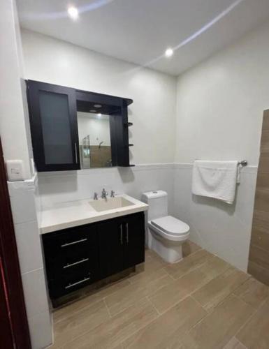 a bathroom with a sink and a toilet and a mirror at Villa Rosa: Modern Colonial Home with Pool in Juan Dolio