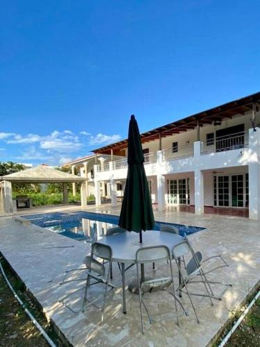 a patio with two chairs and an umbrella in front of a house at Villa Rosa: Modern Colonial Home with Pool in Juan Dolio