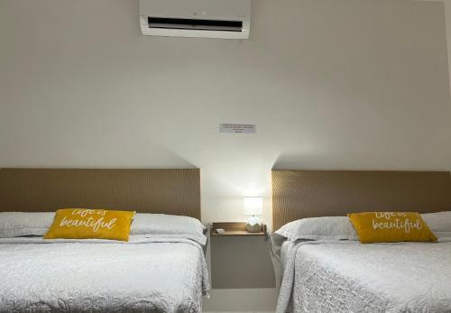 2 camas con almohadas amarillas en una habitación de hotel en EXCELENTE CASA RESIDENCIAL PRIVADO- ALBERCA-SEGURIDAD 24-7-ac, en Ciudad Valles