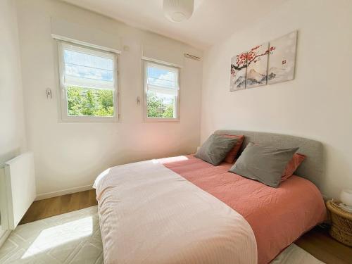 una camera da letto con un grande letto con due finestre di Le Boudoir - 2 pièces et parking a Le Plessis-Robinson