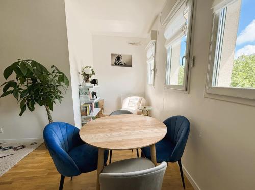 une salle à manger avec une table en bois et des chaises bleues dans l'établissement Le Boudoir - 2 pièces et parking, au Plessis-Robinson