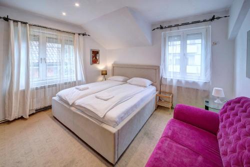 a bedroom with a large bed and a purple couch at Apartmani Pančevo Rose in Pančevo