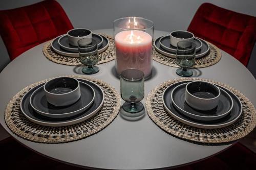 a white table with plates and a candle on it at Home sweet home, cozy apartments, free underground parking, long stays welcome in Vilnius