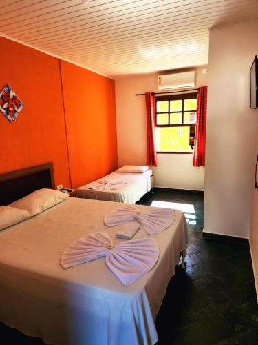 two beds in a room with orange walls at Pousada Viva Ubatuba - GRUPO VIVA UBATUBA in Ubatuba
