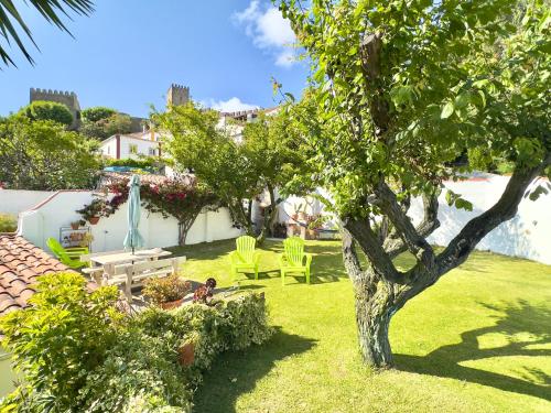 a garden with a table and chairs and a tree at Casa do Candeeiro in Óbidos