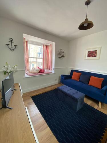 a living room with a blue couch and a window at Cute 1 bed flat in Southwold in Southwold