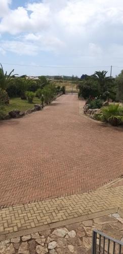 un sentiero in mattoni con alberi e cespugli in un parco di Villa Sorrentina ad Alghero