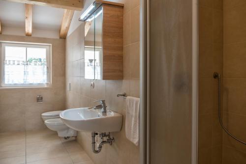 een badkamer met een wastafel, een toilet en een raam bij Apartment Residence Veronika in Ora/Auer