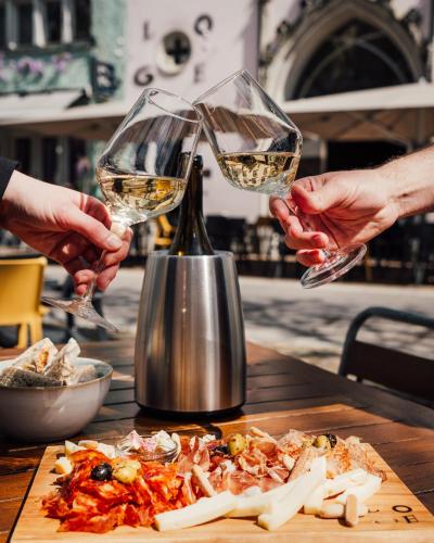 two people holding wine glasses over a table with a pizza at Hotel Loge in Winterthur