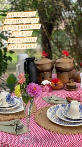 ein Picknicktisch mit Tellern voller Essen und Blumen darauf in der Unterkunft Chalé Céu estrelado in Caruaru
