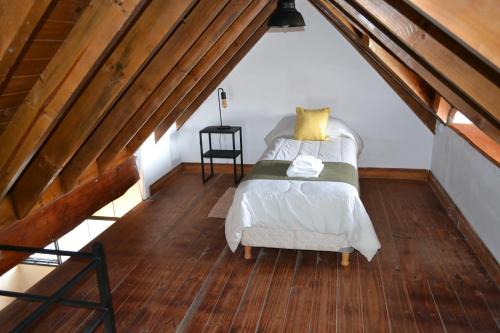 a bedroom with a bed and a chair in a attic at La Balconada by DOT Boutique in Villa Pehuenia