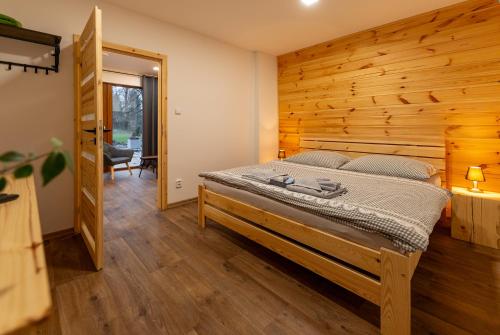 a bedroom with a bed and a wooden wall at Wellness Hotel Koliba in Komorní Lhotka