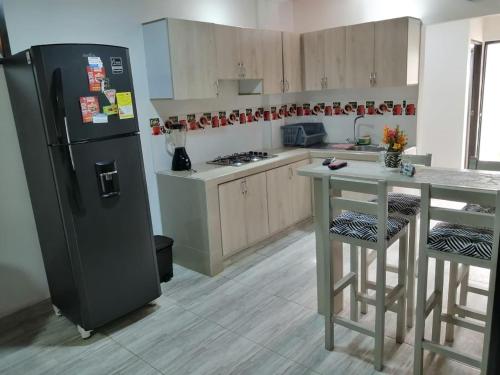 Il comprend une cuisine équipée d'un réfrigérateur noir et d'une table. dans l'établissement apartamento mirador el paraiso 201, à Santa Rosa de Cabal