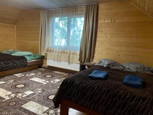 1 dormitorio con 2 camas, ventana y alfombra en Карпатський котедж Karpatian cottage en Vorokhta
