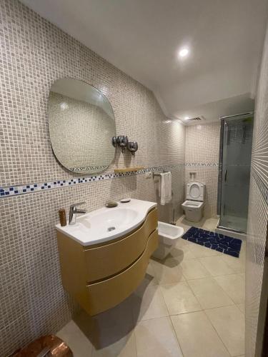 a bathroom with a sink and a toilet and a mirror at Villa 3 chambres piscine marinasmir in Tétouan