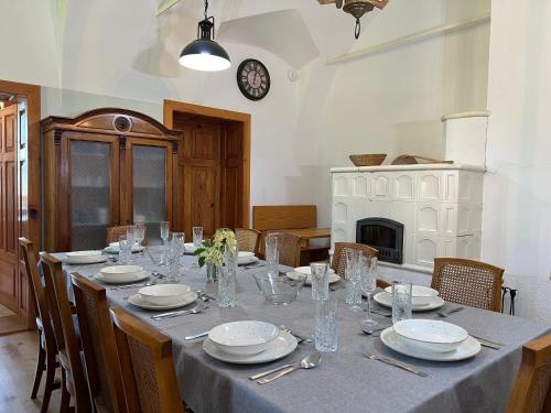 a long table with plates and glasses and a clock at Rezidenca Korman in Fala
