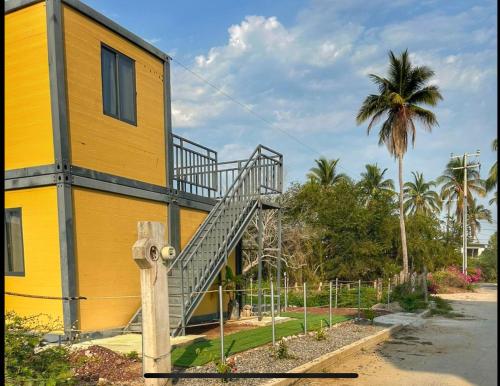 a yellow building with a staircase next to a palm tree at Yellow house 6 minutos de playa in Barra de Navidad